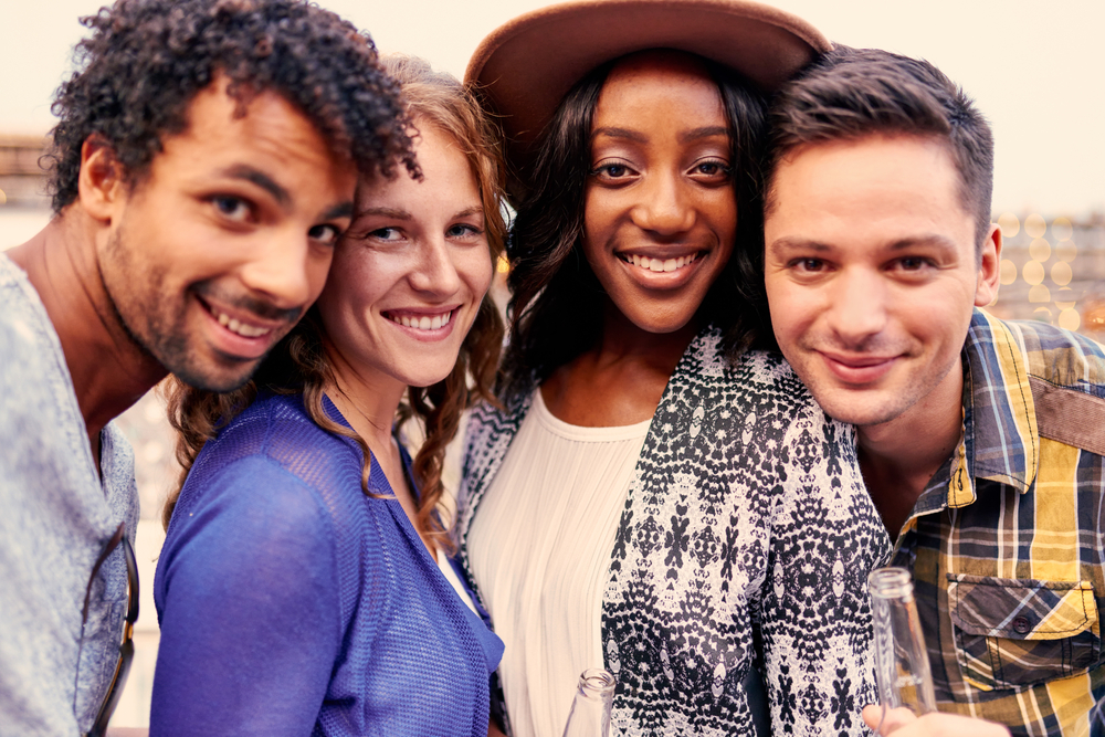 Multi-ethnic millenial group of friends taking a selfie photo with mobile phone on rooftop terrasse at sunset-1